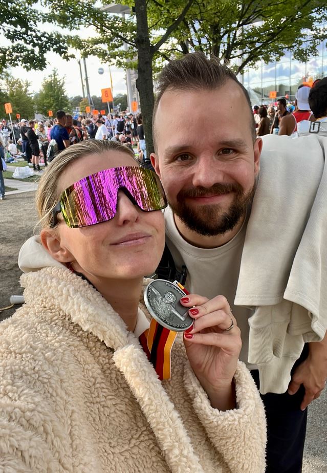 Dagny stands with her partner post-race while wearing sunglasses and her silver medal.