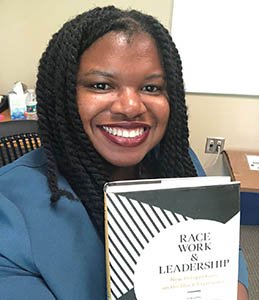 Professor Angelica Leigh holding a copy of Race. Work, and Leadership