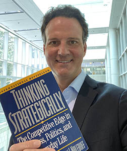 Professor David Ridley holding a copy of Thinking Strategically