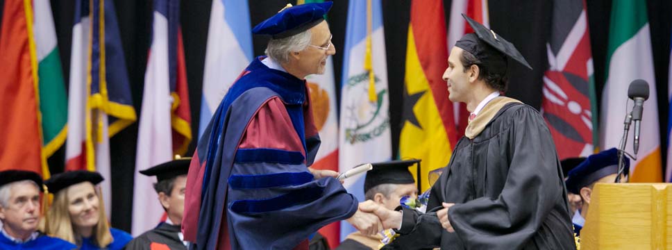 Image of Bill Boulding greeting a graduating student